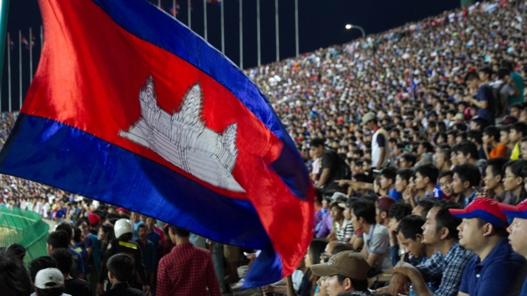 Supporters waving a Cambodian flag in a crowded stadium
